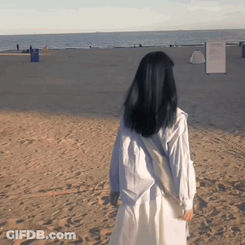 Woman In White Dress Walking On Sandy Beach GIF