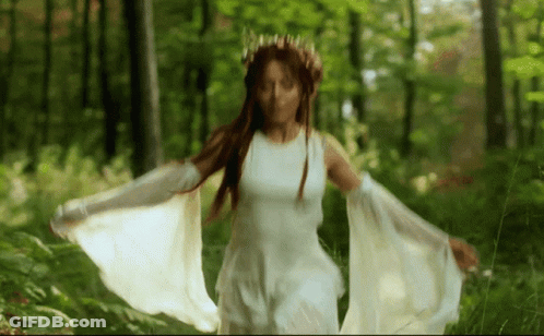 Woman In White Dress With Crown Walking Through Woods GIF
