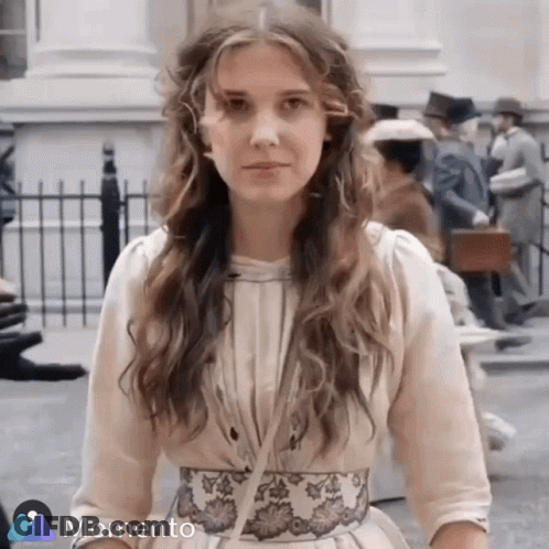 Woman In White Dress With Floral Belt In Front Of Crowd GIF