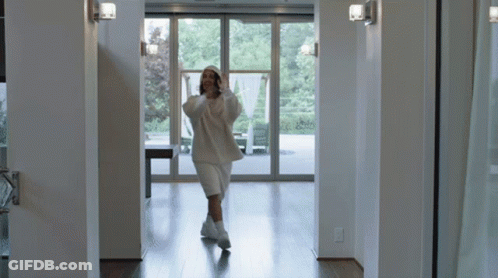 Woman In White Hoodie And Shorts Walking Hallway GIF