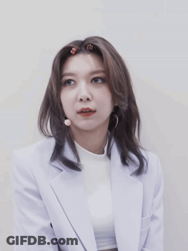 Woman In White Jacket And Turtleneck Looking At Camera GIF
