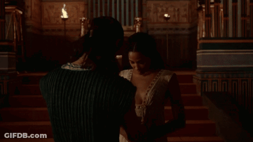 Woman In White Plunging Dress Sitting On Chair GIF
