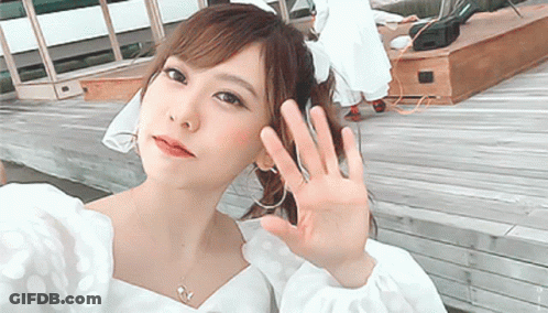 Woman In White Polka Dot Top Waving Hand GIF