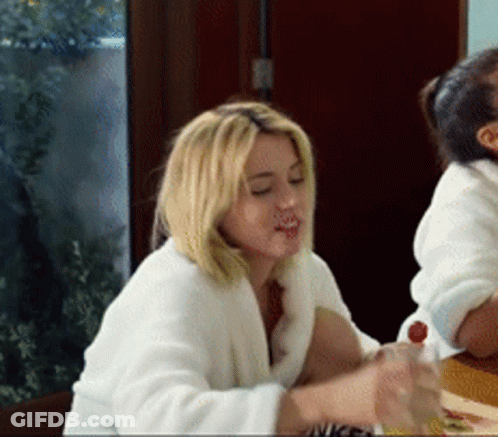 Woman In White Robe Sitting At Table With Juice GIF