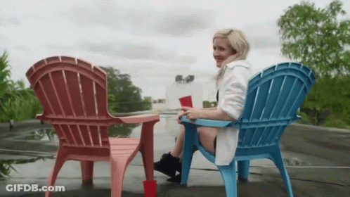 Woman In White Robe Sitting In Pink And Blue Chair GIF