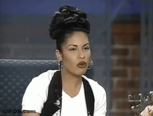 Woman In White Shirt And Black Vest Sitting In Chair GIF