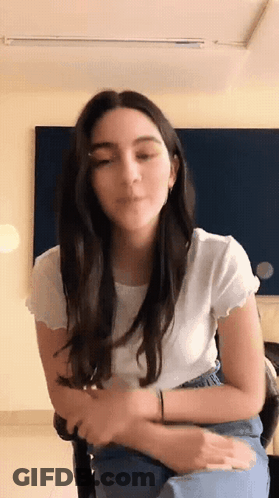 Woman In White Shirt And Blue Jeans Sitting GIF