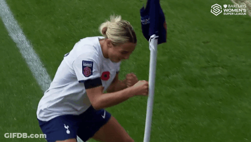 Woman In White Shirt And Blue Shorts Next To Flag GIF