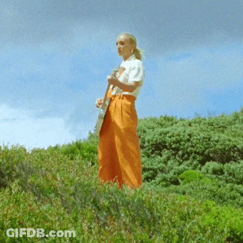 Woman In White Shirt And Orange Pants Playing Guitar GIF