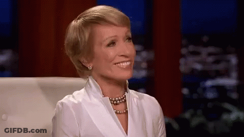 Woman In White Shirt And Pearl Necklace Smiling On Couch GIF