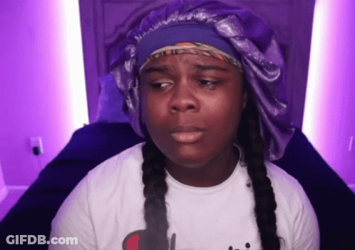 Woman In White Shirt And Purple Hat Sitting On Bed GIF
