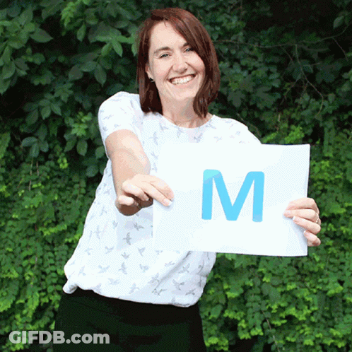Woman In White Shirt Holding Sign That Says M GIF