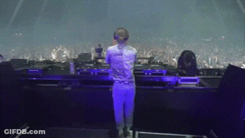 Woman In White Shirt In Front Of Purple Stage Lights GIF