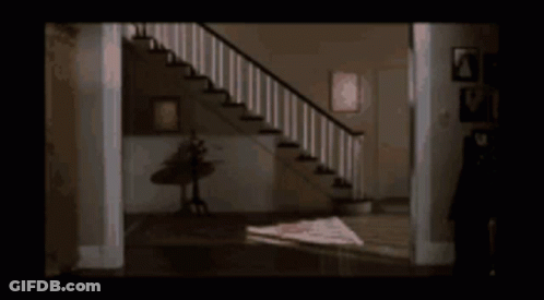 Woman In White Shirt In Hallway By Stairs GIF
