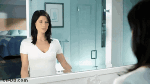 Woman In White Shirt Looking In Bathroom Mirror GIF
