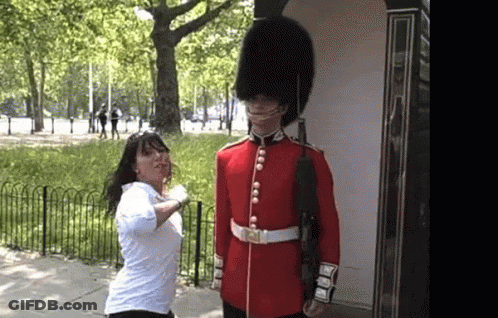 Woman In White Shirt Next To Man In Red Uniform GIF