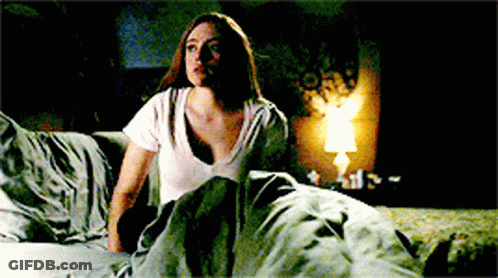 Woman In White Shirt Sitting On Bed With Lamp GIF