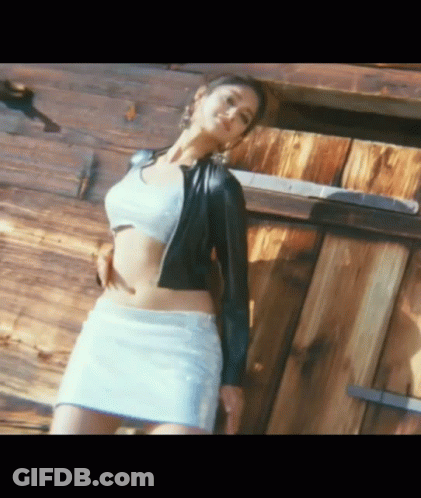 Woman In White Skirt And Black Jacket At Wooden Building GIF