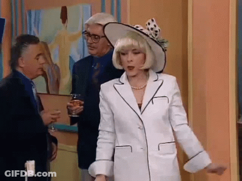 Woman In White Suit And Hat Standing Before Two Men GIF