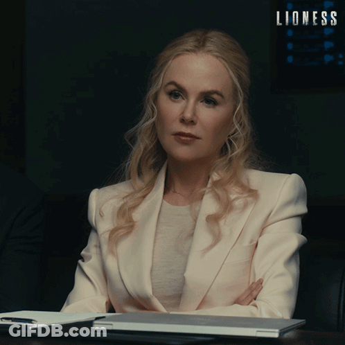 Woman In White Suit At Desk With Lioness Sign GIF