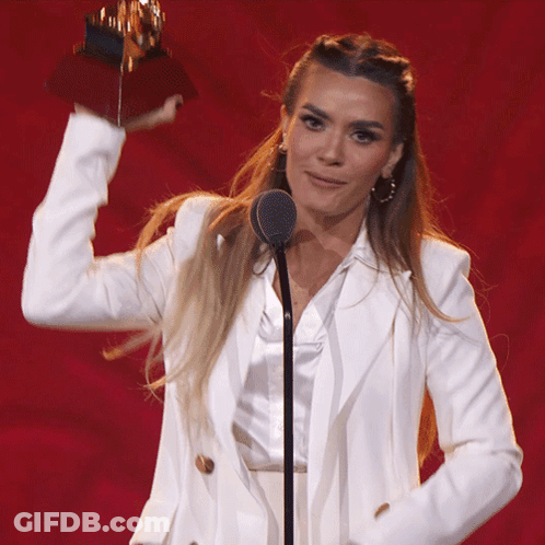 Woman In White Suit Holding Trophy GIF