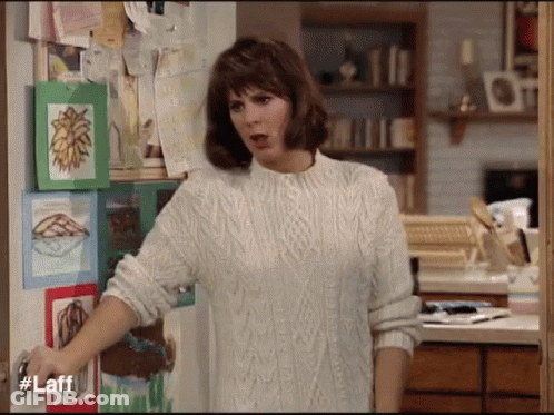 Woman In White Sweater In Front Of Door With Laff GIF