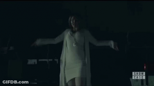 Woman In White Sweater In Front Of Show Case Sign GIF