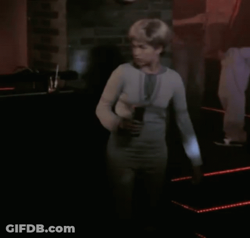 Woman In White Sweater Standing In Dark Room GIF