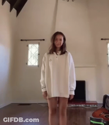 Woman In White Sweater Standing In Living Room GIF