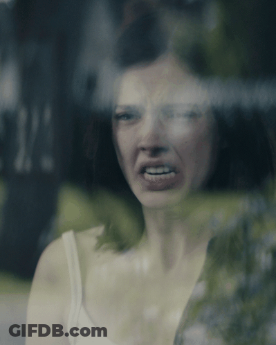 Woman In White Tank Top Making Funny Face At Window GIF