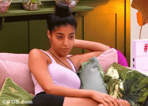 Woman In White Tank Top Sitting On Couch With Pillows GIF