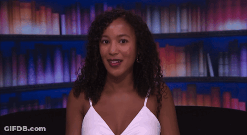 Woman In White Tank Top Smiling At Bookshelf GIF