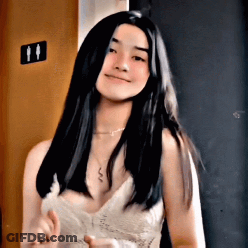 Woman In White Tank Top Standing In Front Of Toilet Sign GIF