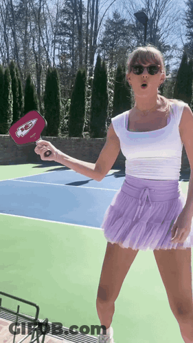 Woman In White Top And Purple Skirt Holding Chiefs Paddle GIF