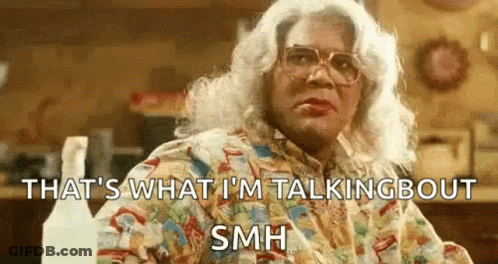 Woman In Wig And Glasses Sitting With Spray Bottles GIF