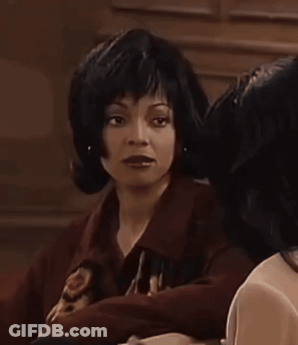 Woman In Wig Beside Woman In Dark Room GIF