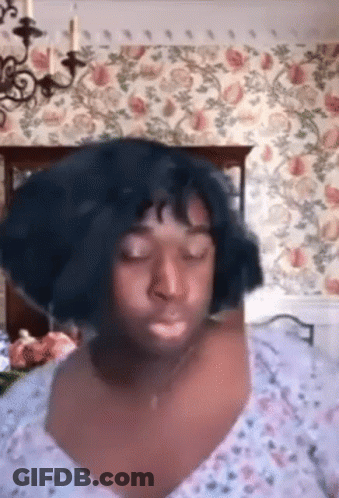 Woman In Wig Sitting On Bed Eyes Closed GIF