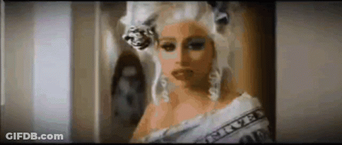 Woman In Wig With Dollar Bill Around Shoulder GIF