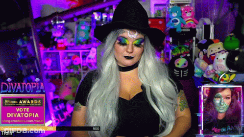 Woman In Witch Costume In Front Of Divatopia Banner GIF
