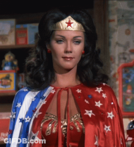 Woman In Wonder Woman Costume In Front Of Bookshelf GIF