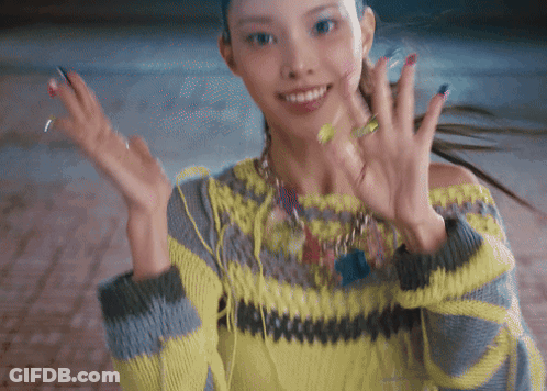 Woman In Yellow And Grey Sweater Smiling And Waving GIF
