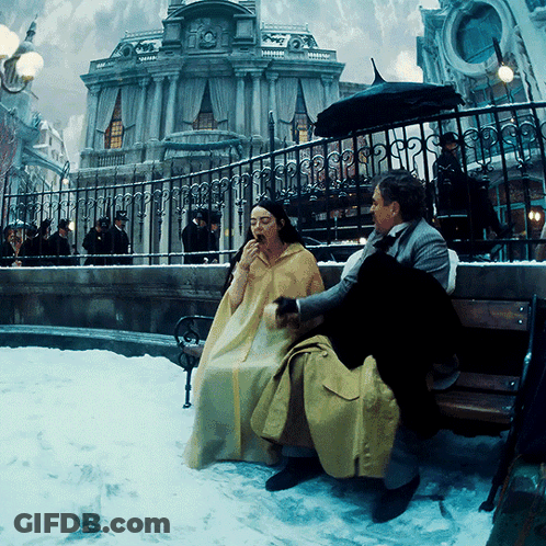 Woman In Yellow Cape Sitting On Bench GIF