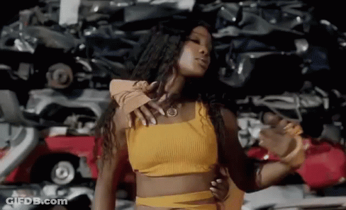 Woman In Yellow Crop Top Dancing In Front Of Car Pile GIF