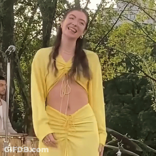 Woman In Yellow Dress At Microphone On Stage GIF