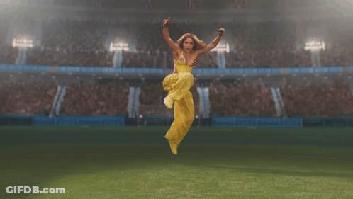 Woman In Yellow Dress Jumping On Soccer Field GIF