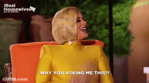 Woman In Yellow Dress Sitting In Orange Chair Saying Why You Asking Me This GIF