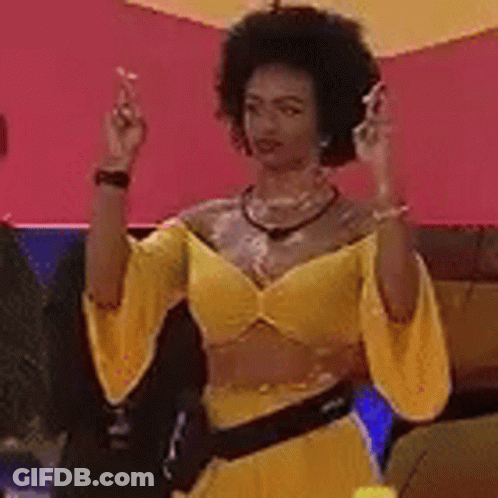 Woman In Yellow Dress Sitting On Couch With Hands In Air GIF