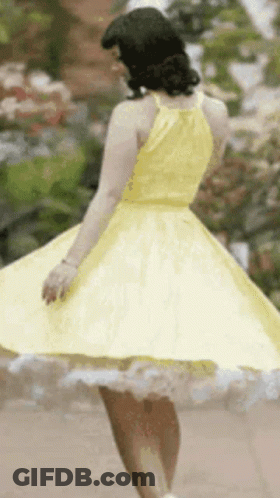 Woman In Yellow Dress Spinning In Garden GIF
