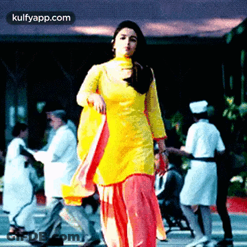 Woman In Yellow Dress Standing Before Crowd GIF
