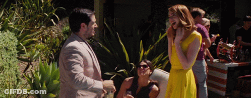 Woman In Yellow Dress Talking To Man In Suit GIF